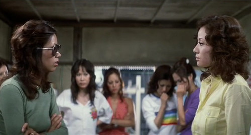 From the film 'Girl Boss Guerilla', a screenshot of several female gangsters facing off in a room.